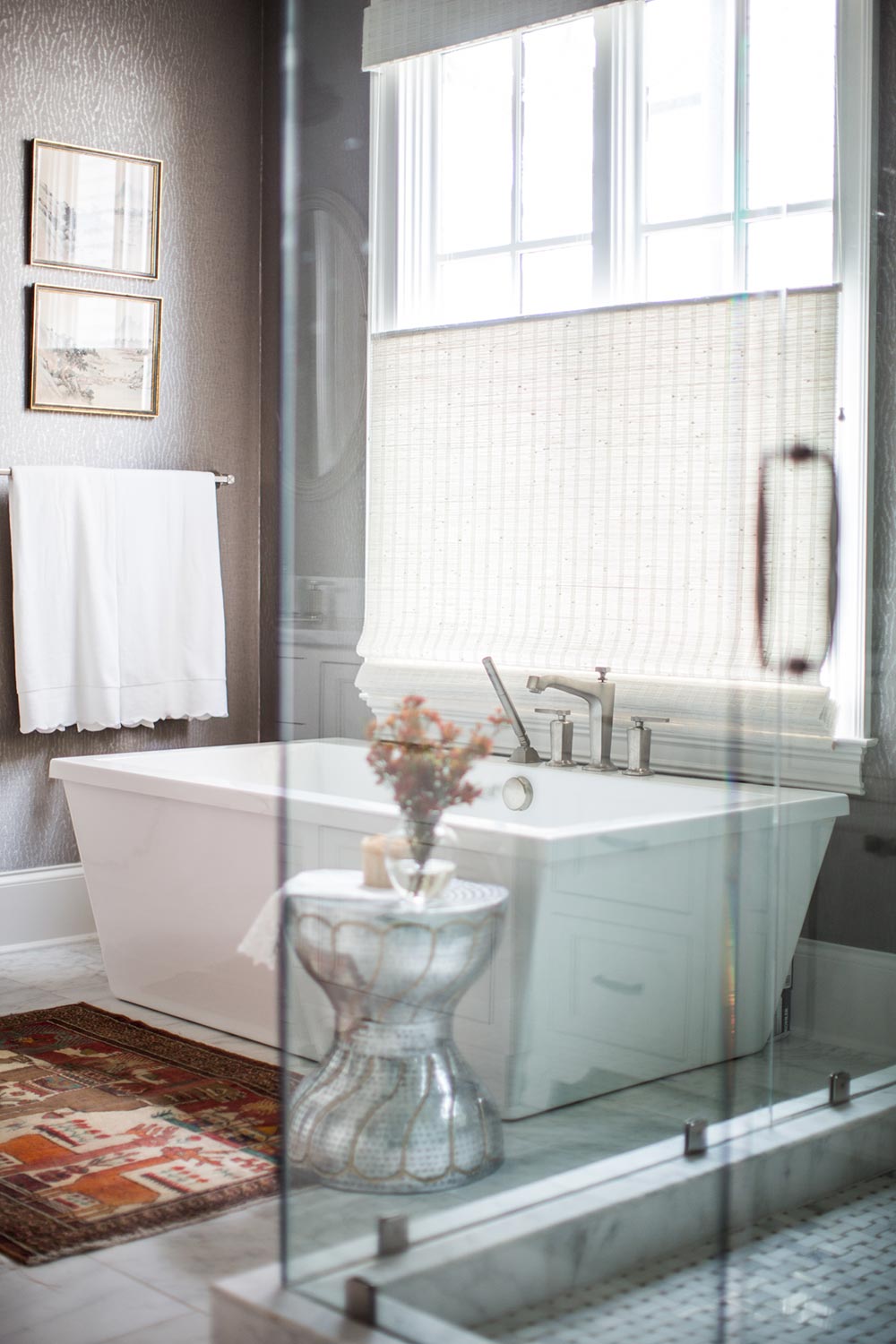 Large rectangle statement bathtub. Moody bathroom wallpaper. Tub side table. Large bathroom window with natural lighting.