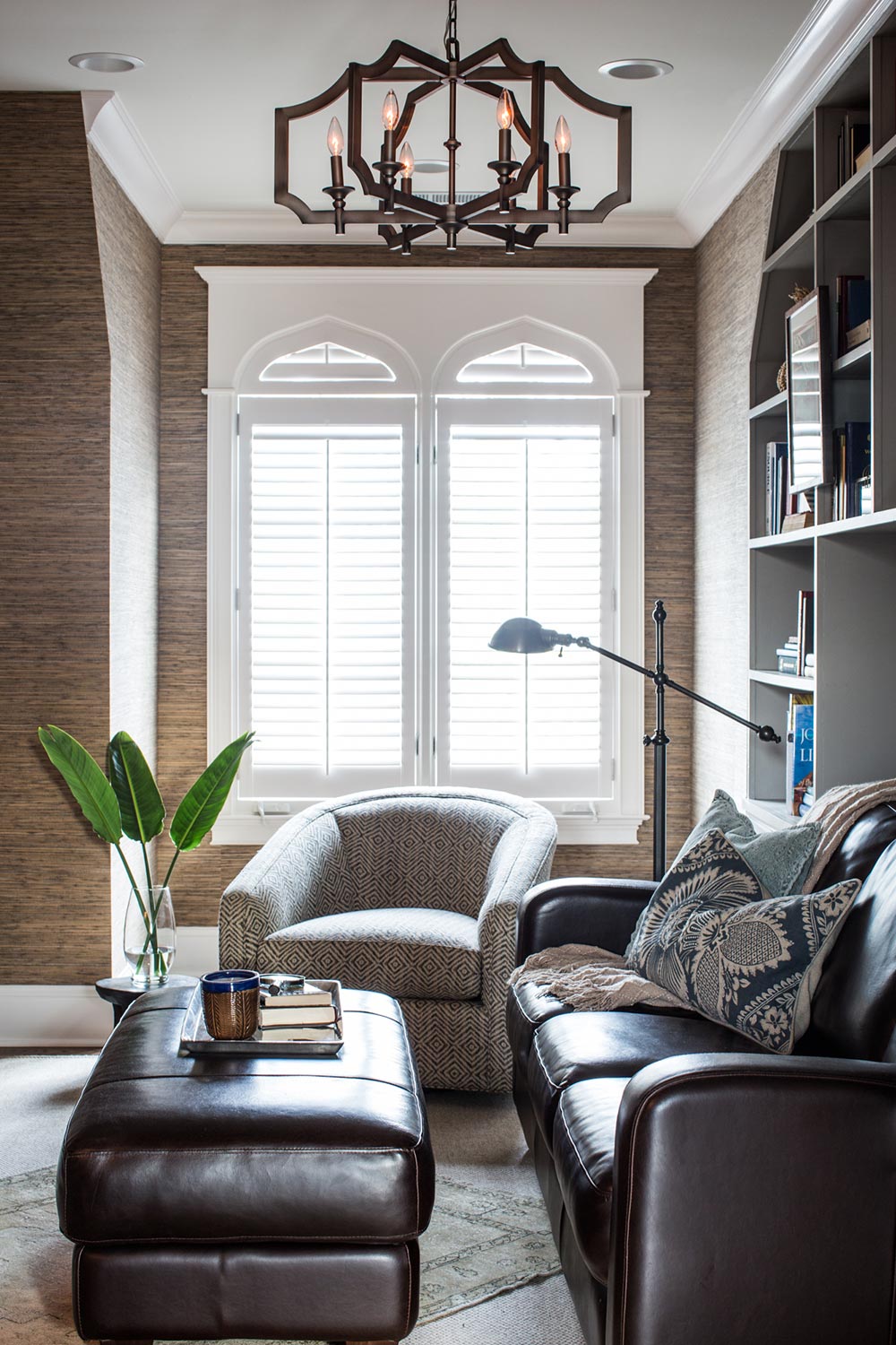 Moody library. Dark grass cloth wallpaper. Chic leather furniture. Library built-ins. Statement chandelier 