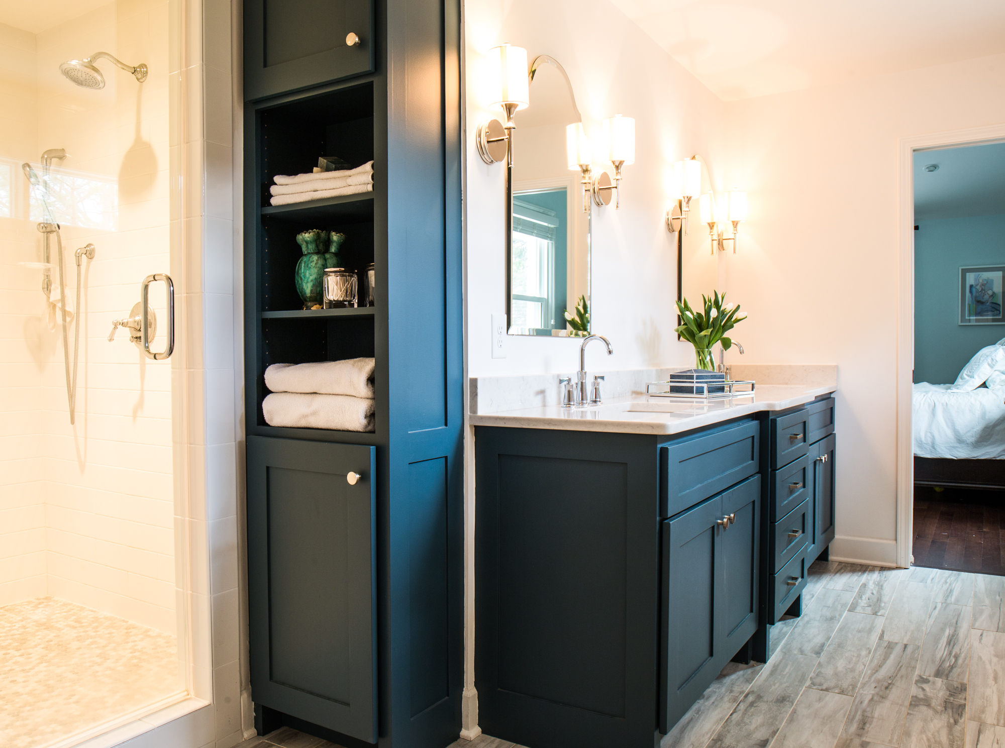 White bathroom counters. Dark blue bathroom cabinets. Built in linen shelving.