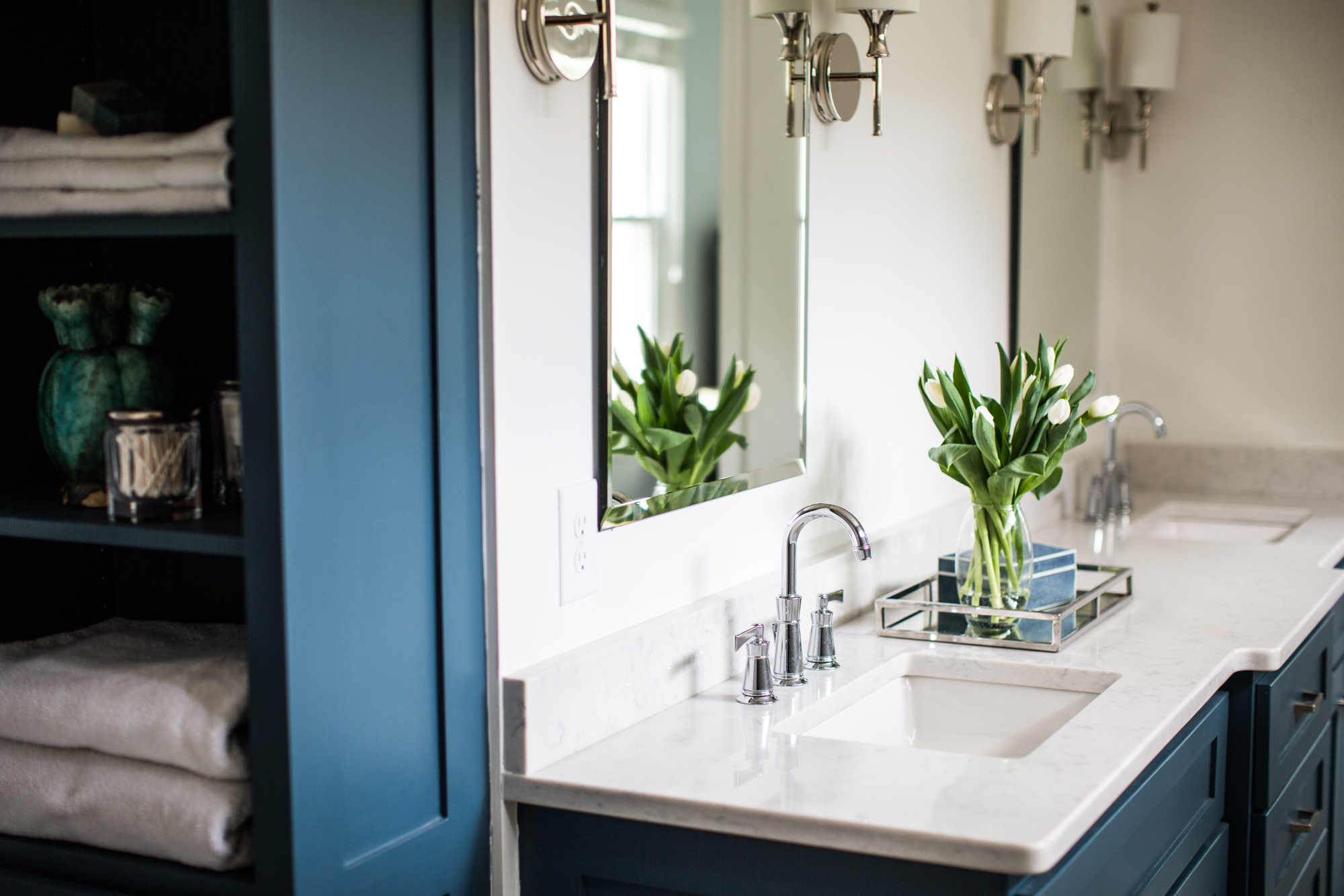 White bathroom counters. Dark blue bathroom cabinets. 