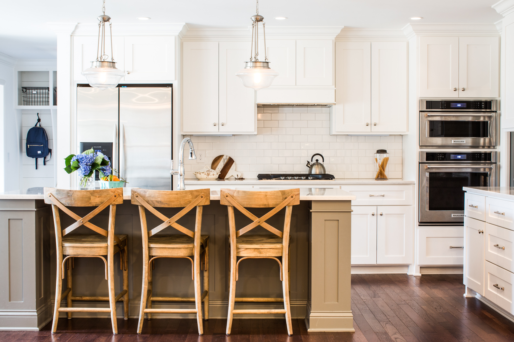 White kitchen. Subway tile backsplash. Dark wood flooring. Natural wood bar stools.