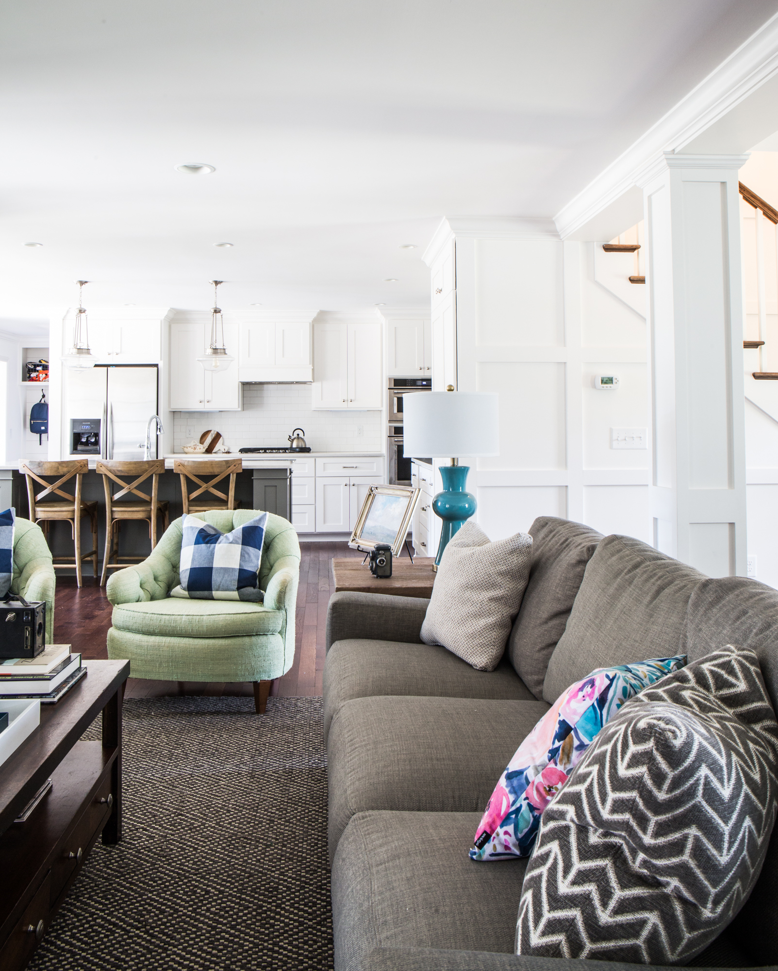 White kitchen with attached living room. Green accent chairs.