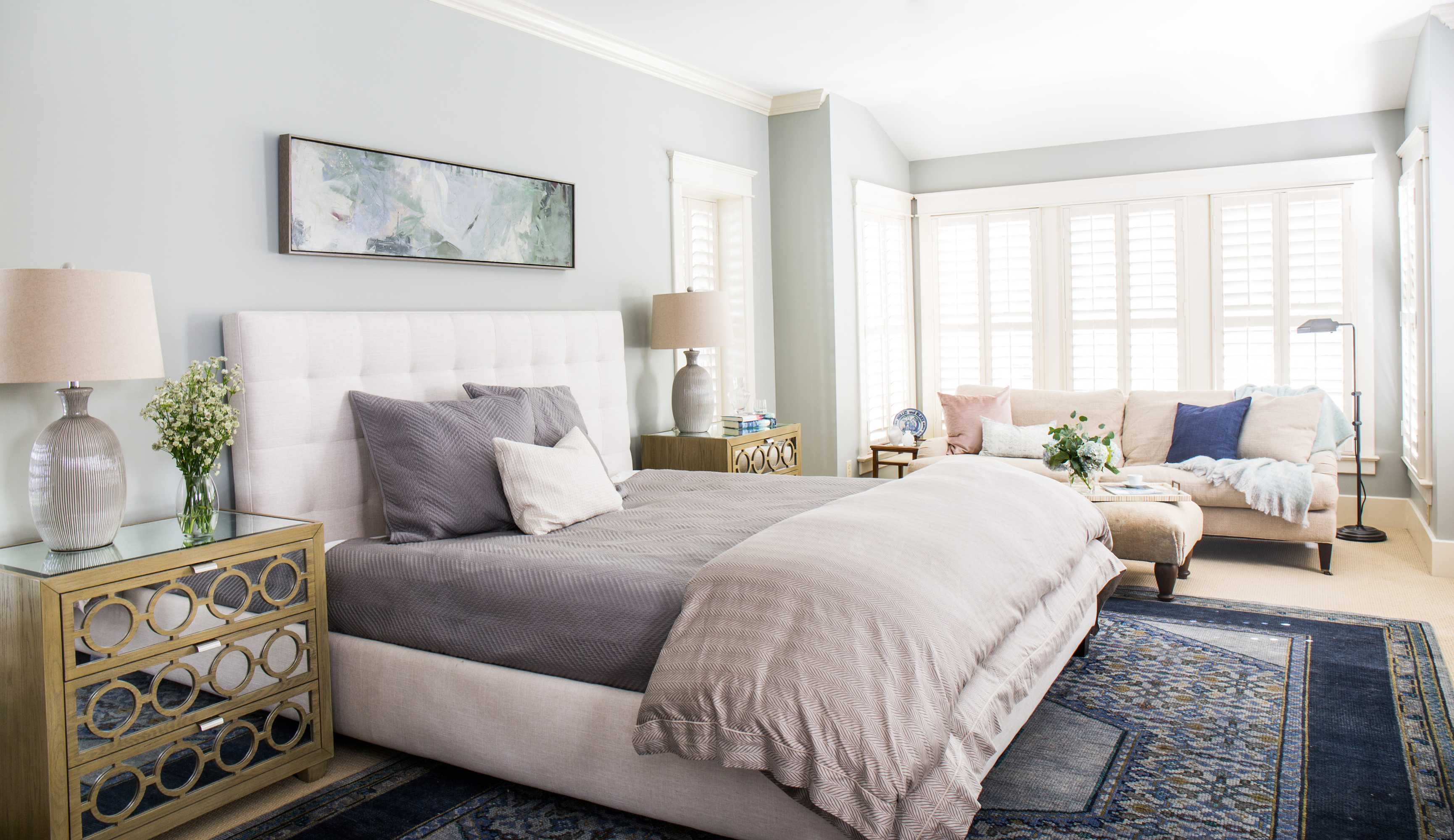 Stunning light and bright bedroom. Blue bedroom walls. Neutral and timeless bedroom. White bed with gold side tables.
