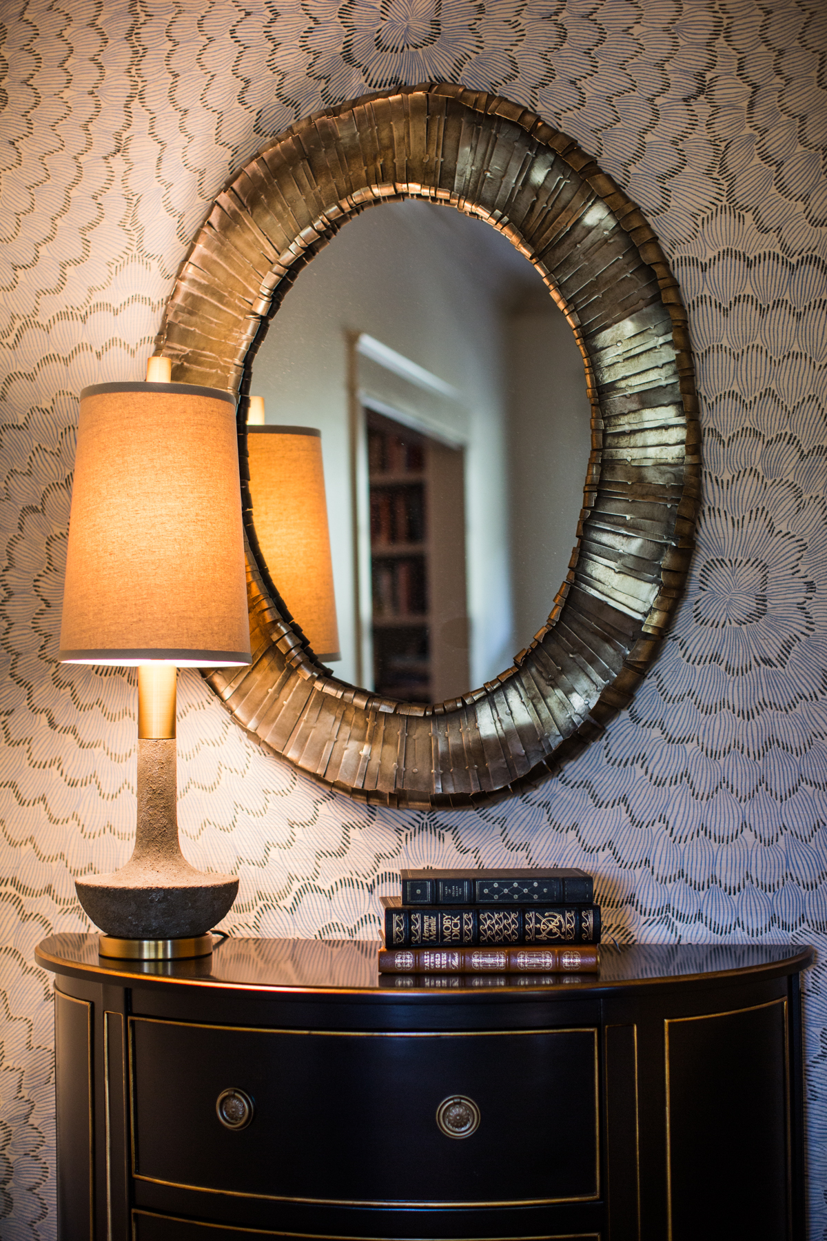Fold textured mirror. Neutral wallpaper with fun design. Black antique side table