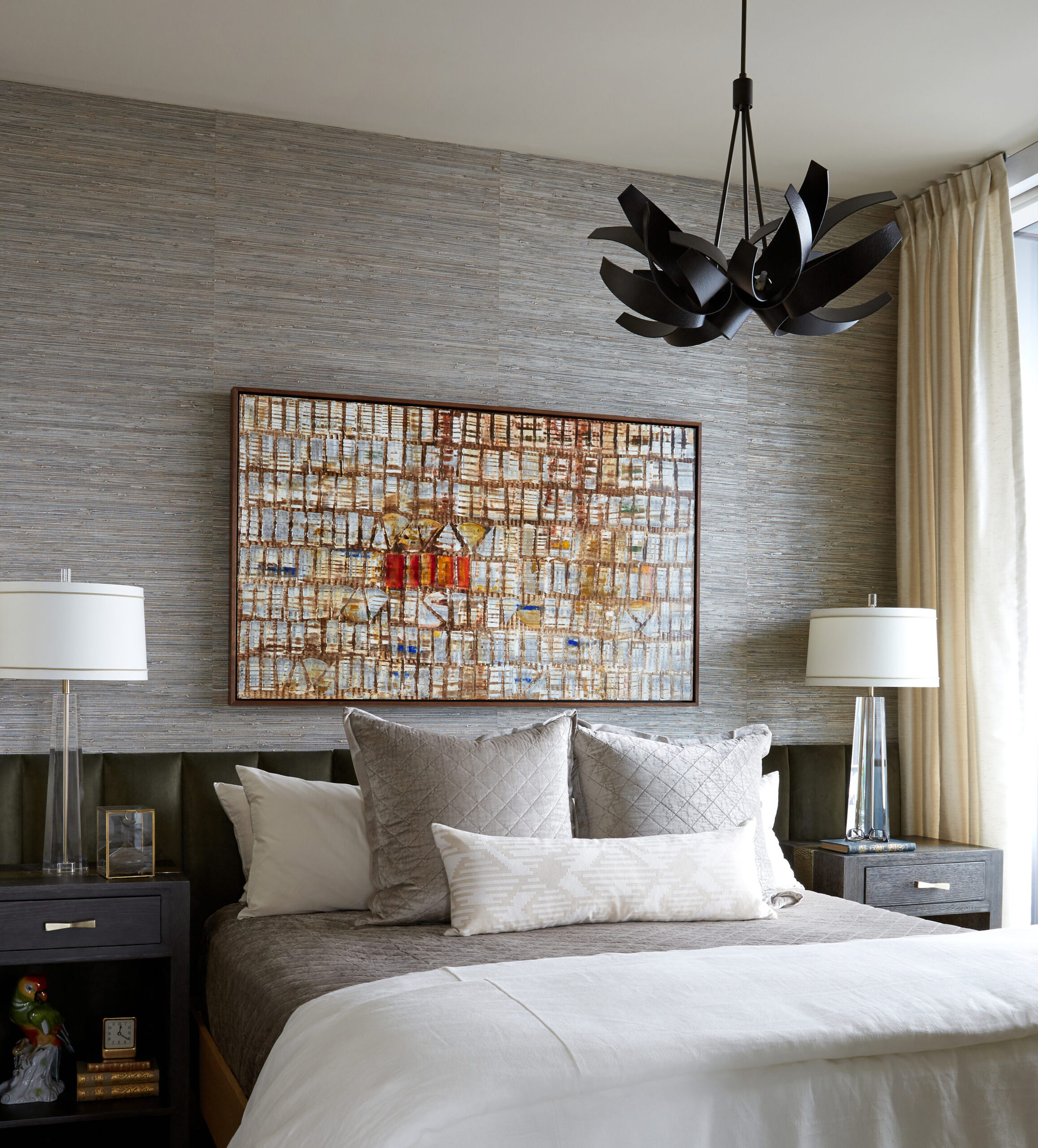 Cozy bedroom with statement art. Statement chandelier in bedroom. Textured accents. Upholstered headboard the length of the wall.